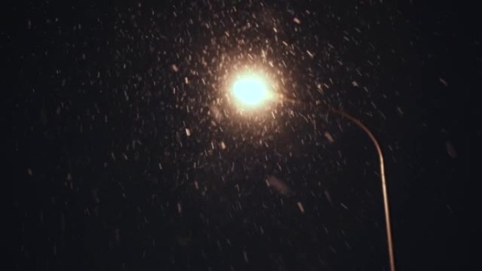 灯笼背景下夜间异常降雪。雪落在镜头里。底视图。