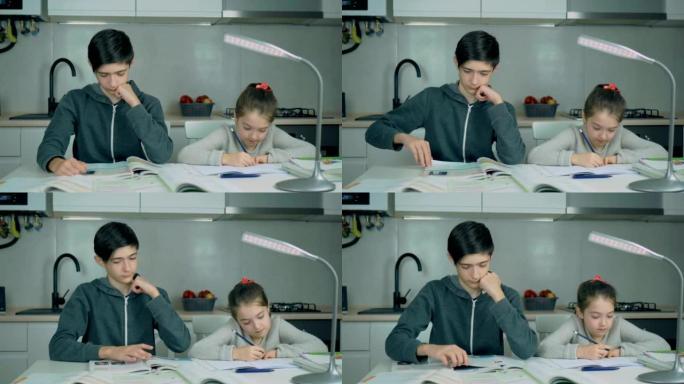 年轻的中学男孩和妹妹一起在家做作业
