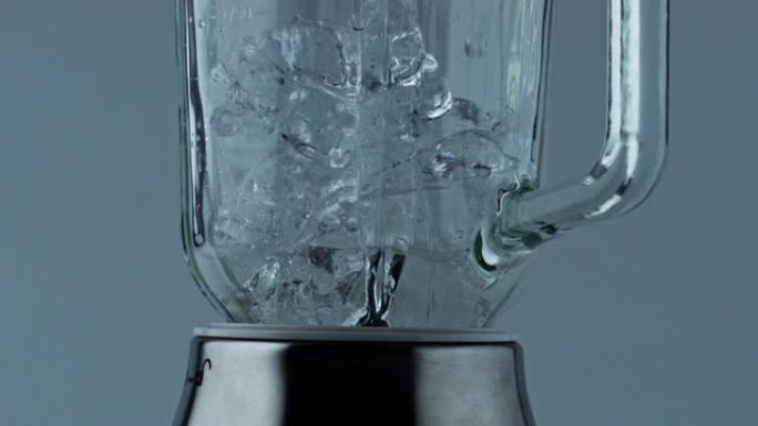 冰块掉落搅拌机容器特写。加冰的研磨机灌装