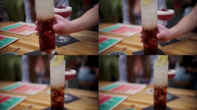 一只手在桌子上摆放高大的长岛冰茶饮料的特写镜头