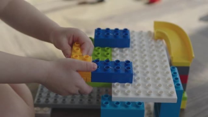 幼儿用手指用明亮的彩色砖块建造建筑