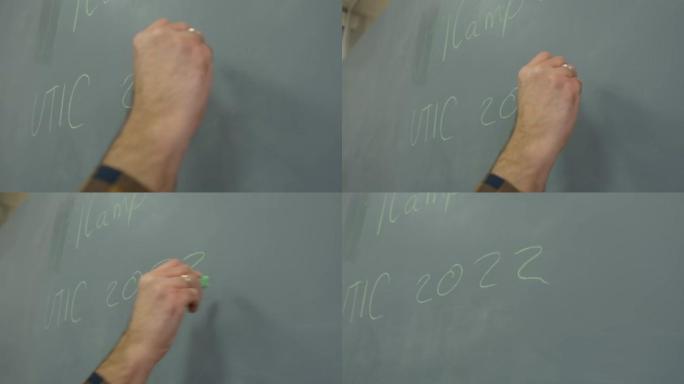男性用粉笔在黑板上书写2022年。特写