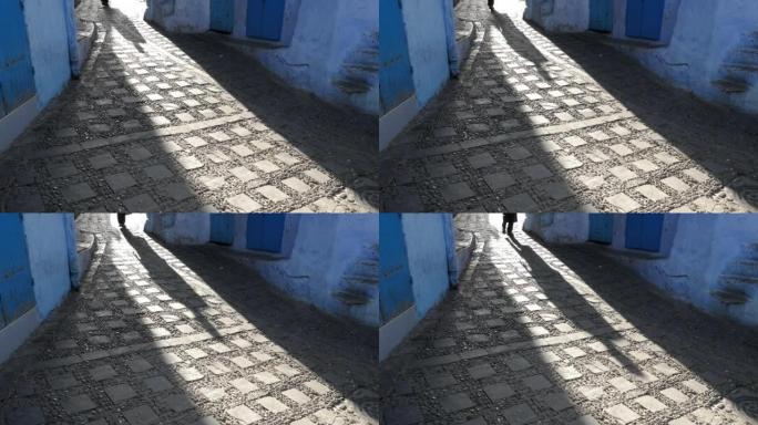 在摩洛哥的蓝色城市Chefchaouen中行走的人的影子的街景。舍夫沙万的麦地那是著名的旅游目的地。