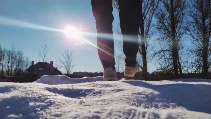 冬季阳光明媚的户外冰上滑倒的男人的特写镜头，后视图。男子脚在雪道滑行低角度视野慢动作