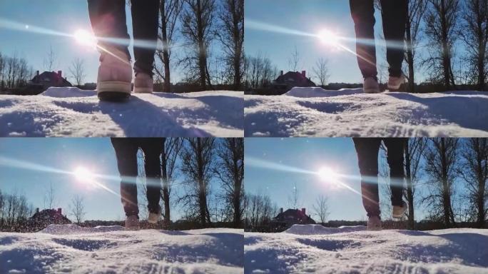 冬季阳光明媚的户外冰上滑倒的男人的特写镜头，后视图。男子脚在雪道滑行低角度视野慢动作