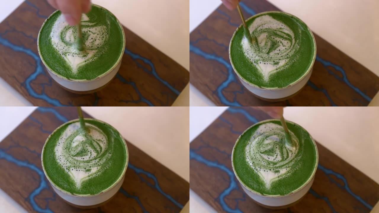 一杯带有绿色泡沫的抹茶的特写镜头。一杯热牛奶和蔬菜奶，咖啡的替代品。美味而令人振奋的抹茶绿茶饮料可全