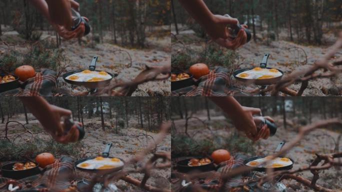 在森林里野餐时，双手慢动作用黑胡椒粉煎鸡蛋