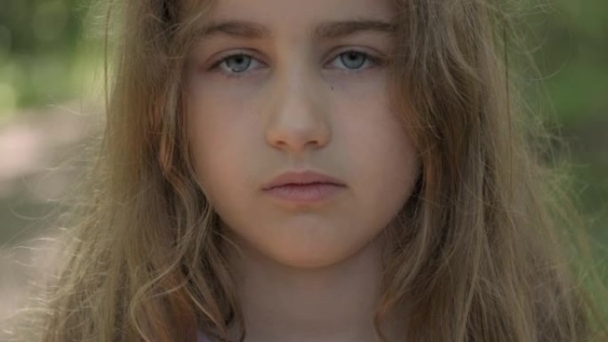 人脸。年轻严肃的金发少女看着相机。肖像可爱严肃的孩子严肃的忧心忡忡的高加索少年。悲伤自信的小女孩。