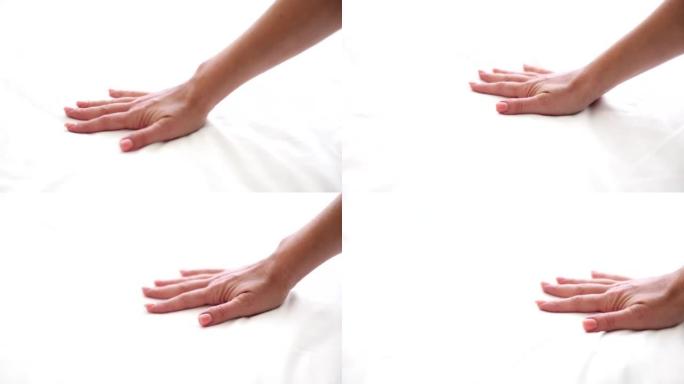 女人正在触摸柔软舒适的床垫或手的白色床单特写