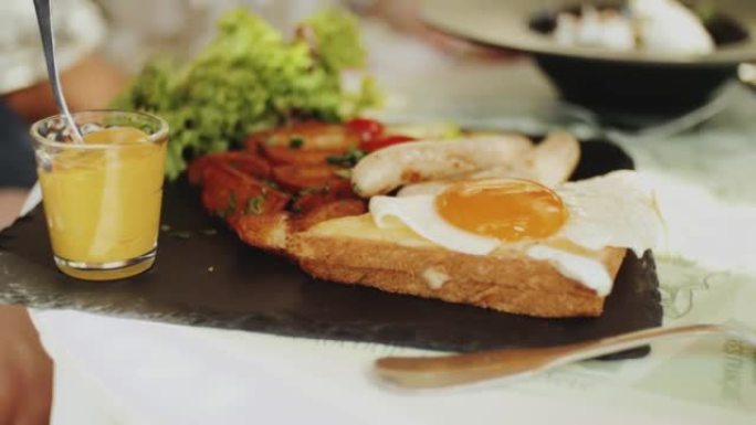 鸡蛋本尼迪克特在夏季咖啡馆，美式早餐，人手叉子，健康食品。