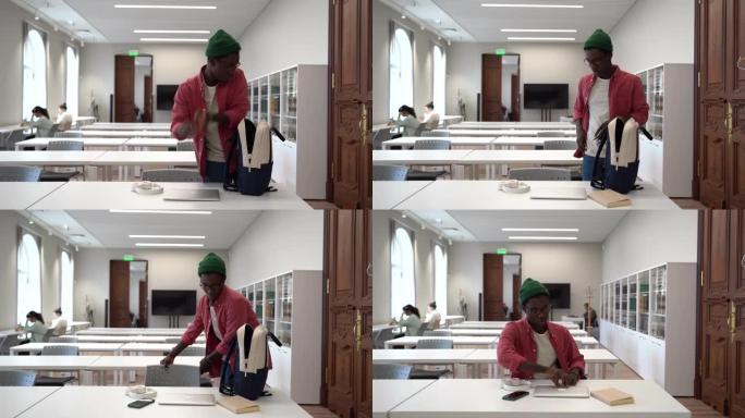 黑人学生从背包里拿出笔记本电脑学习坐在图书馆准备好的工作场所。