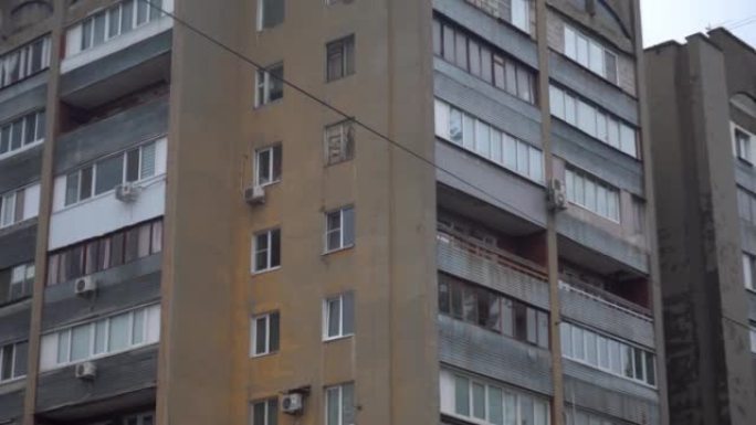一座小型苏联公寓楼。苏联解体后留下的褪色建筑。混凝土建筑，阳台，从下到上全景。灰色的多云的天气。