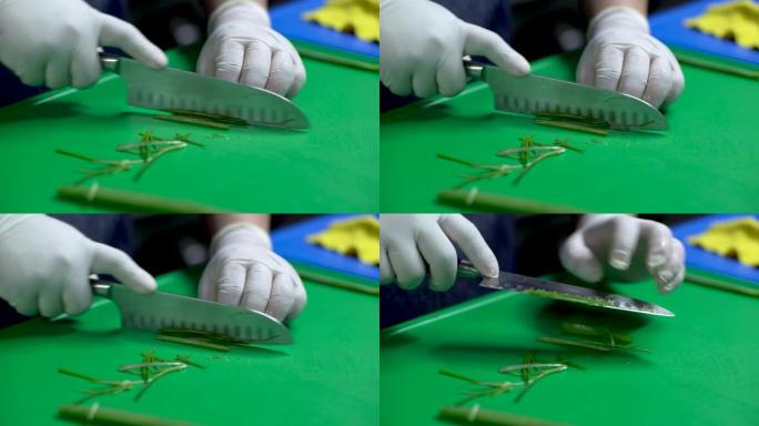 一名戴着白手套的男子用锋利的刀在绿色板上切葱的镜头