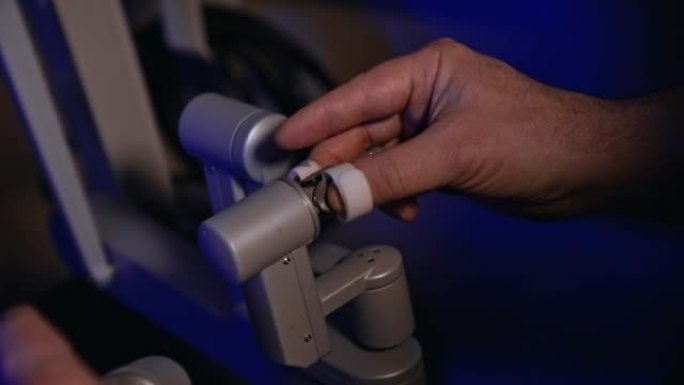 男性手在手术室移动机器人设备的灵敏旋转手柄。人工操作的手术机器人。特写。
