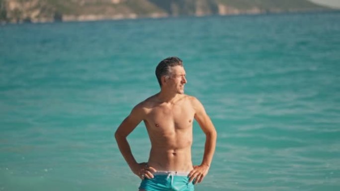 游泳后，在爱琴海Oludeniz海滩的地中海碧绿海水中，放松肌肉发达的运动员在海滩上。夏季旅游季节费