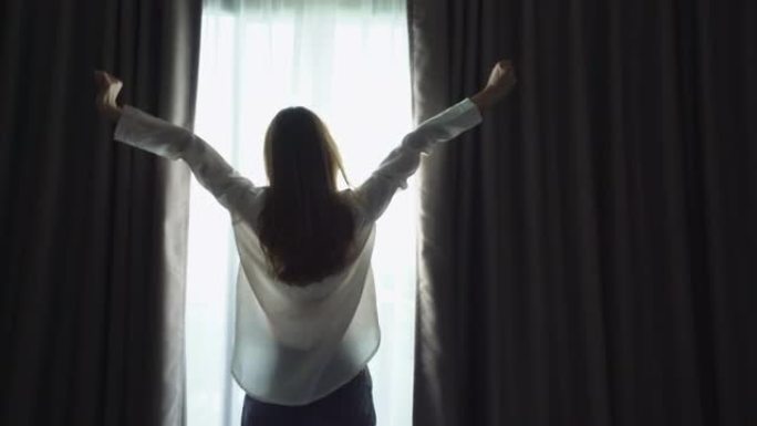 一个亚洲女孩早上打开窗帘在窗户前伸展的特写高清镜头