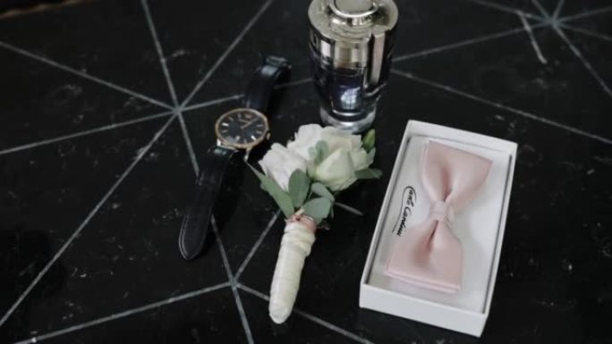 手表的特写镜头，盒子里的领结，香水和桌子上的扣眼