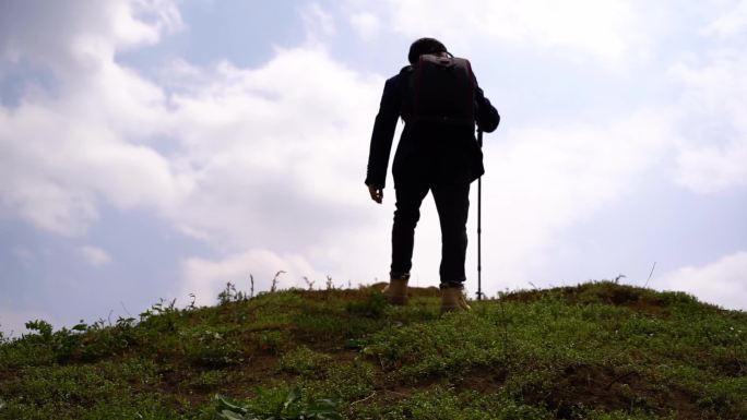 西装男士徒步登山山顶 登山杖白云