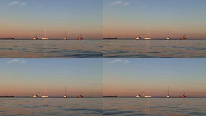 日落时海上地平线上的几艘船。温暖的夏夜。
