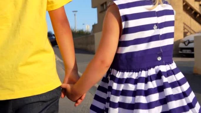 男孩和一个小女孩牵着手走在一起的特写镜头