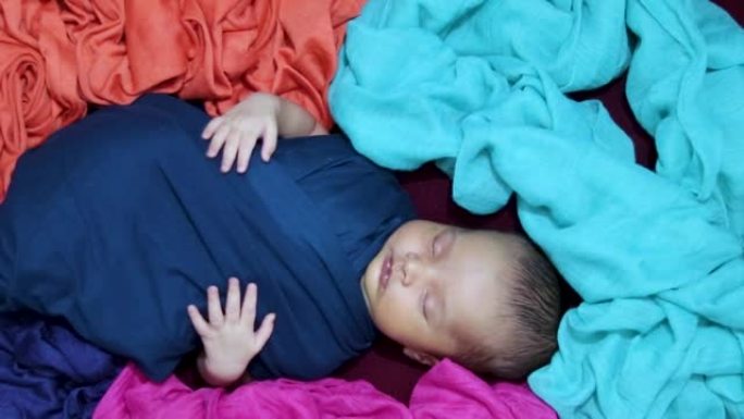 可爱的新生儿睡在婴儿裹在独特的风格从顶部角度拍摄