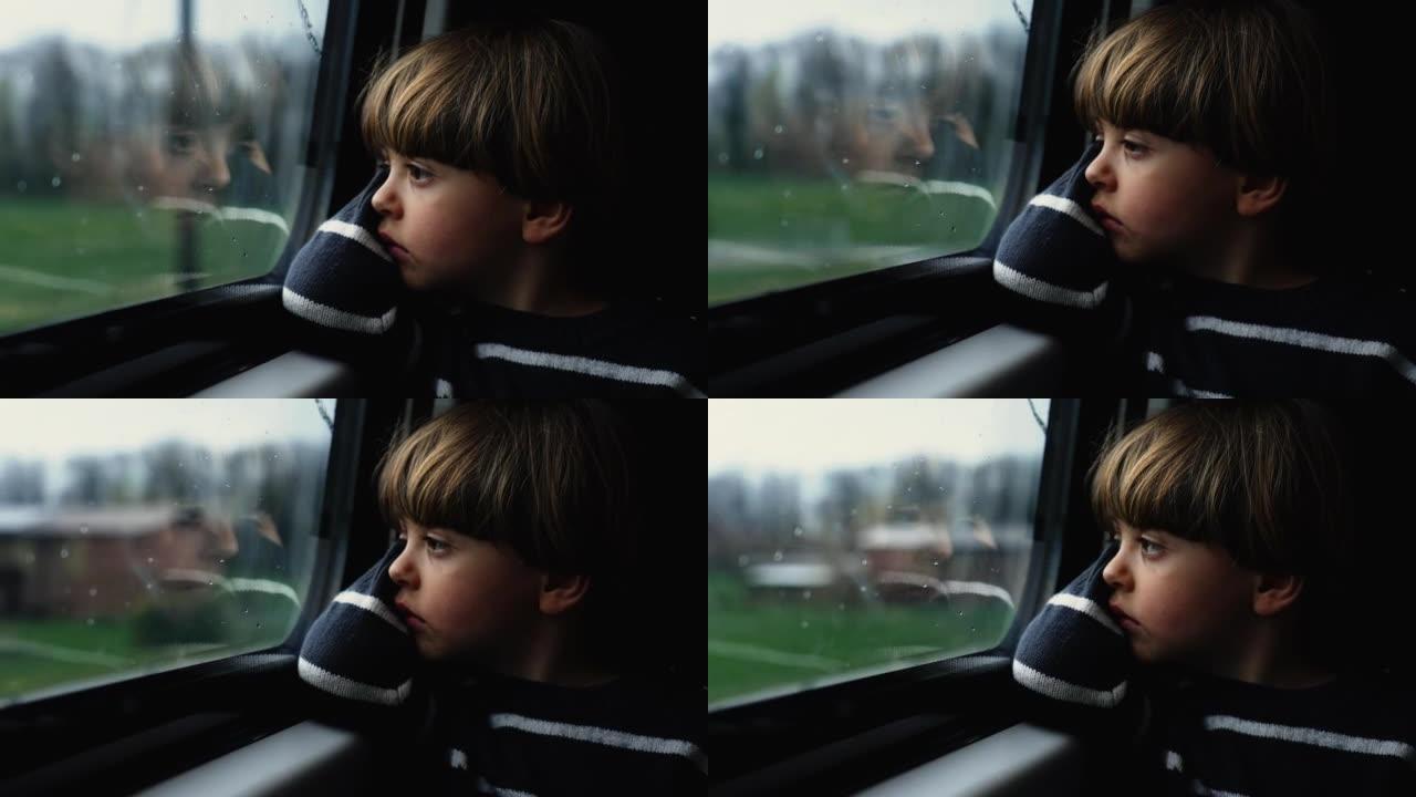 体贴的孩子盯着火车窗户感到悲伤。忧郁的乘客男孩在灰色的喜怒无常的日子里乘坐现代交通工具旅行