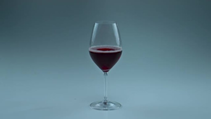 特写红酒掉落玻璃。玫瑰小酒溅在干净的高脚杯里