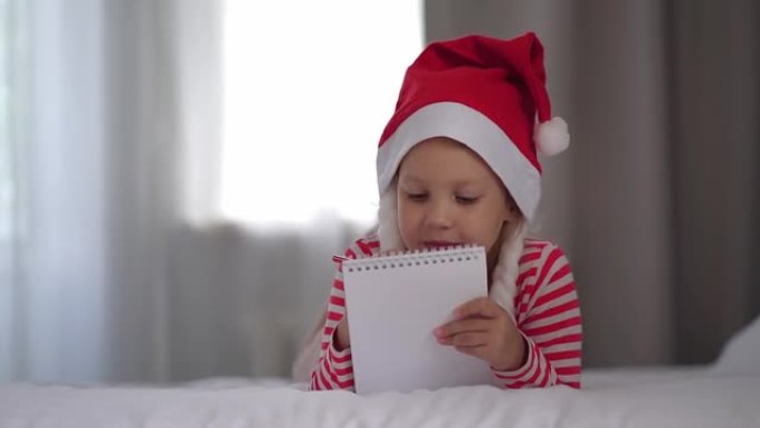 戴红色圣诞帽的女孩给圣诞老人写了一封信