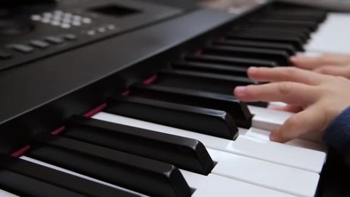 儿童的手指在钢琴合成器的琴键上弹奏。选择性聚焦钢琴按键