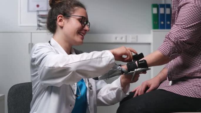 年轻的女医生为年轻的残疾男子贴上仿生机器人手假肢