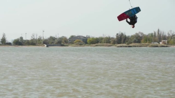 风筝冲浪者骑着风筝在海湾做和练习技巧。自由式风筝跳跃，在池塘风筝上训练。喜欢骑行的风筝冲浪者。极限水