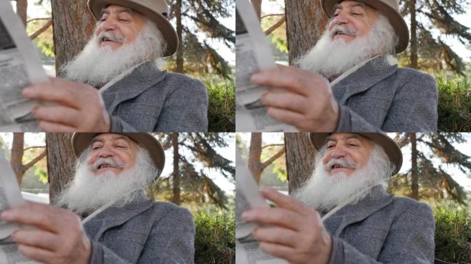 开朗的微笑的老人，留着茂密的胡须，戴着帽子，在公园的长椅上读报纸，说些微笑着摇摇头的东西。关于主要新