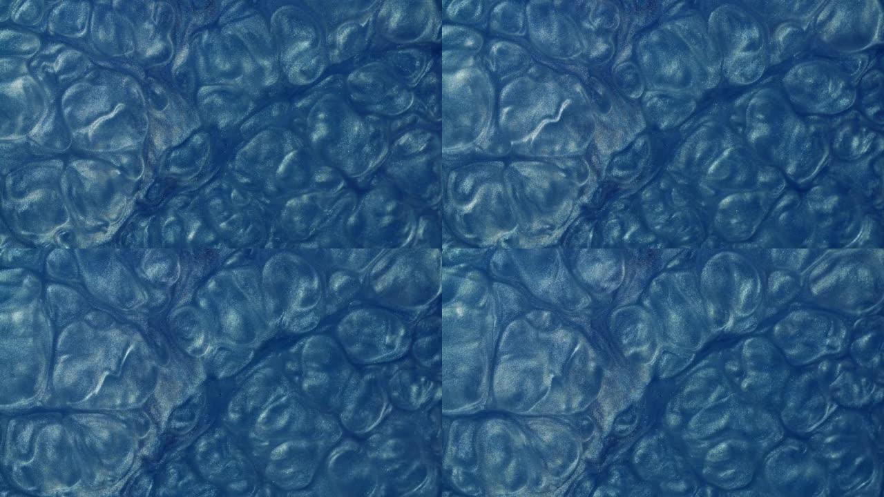 沸腾的蓝色银色液体粒子创造了抽象的背景。闪闪发光的银粉在水中形成美丽的形态，金属的银色纹理在运动中
