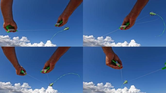 成人手拿着绿色线盘放飞绿色风筝的惊人观点。背景是蓝天白云。慢动作