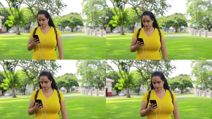 一名西班牙裔妇女带着白色有线耳塞和一部智能手机在巴拿马公园散步的高清视频