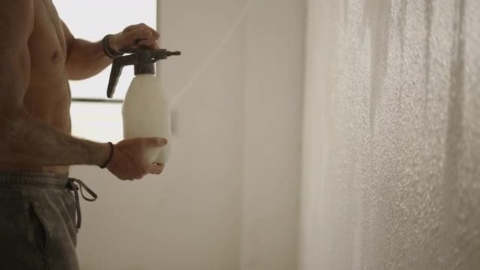 无法识别的杂工在家里的白色墙壁上喷洒油漆-慢动作拍摄