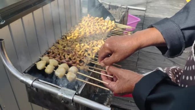 有人在烹饪节上烧烤肉丸和用竹子串烧的鸡肠，出售