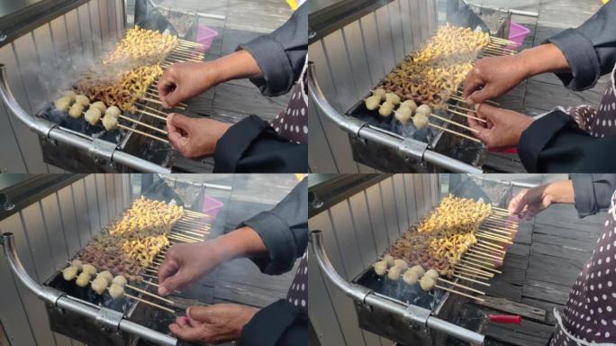 有人在烹饪节上烧烤肉丸和用竹子串烧的鸡肠，出售