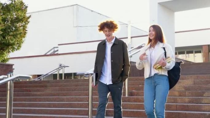 两个时髦的学生走在校园附近，微笑着。友好的白人男孩和女孩一起走在大学附近。慢动作