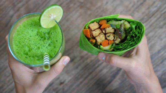 健康美味的纯素食食品和绿色芹菜汁的完美健康快捷午餐。从上面拍摄相机在人类手中吃午饭。
