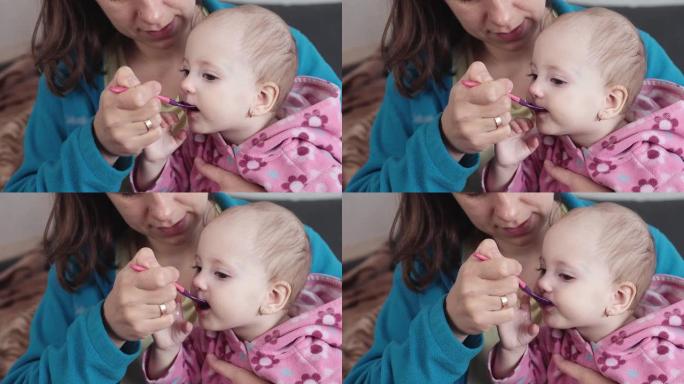 母亲用勺子给婴儿咳嗽药。