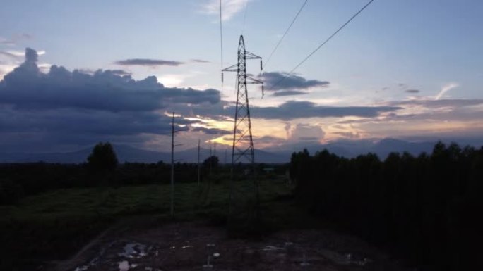 高压塔基础施工现场的无人机镜头。乡村日落时天空中电线杆和电线的轮廓。