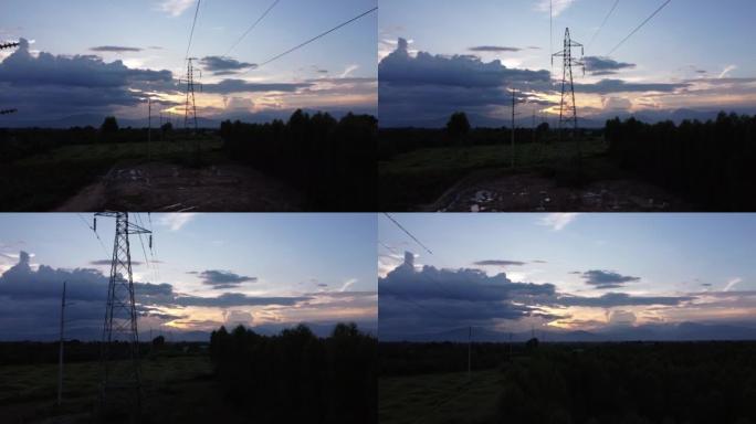 高压塔基础施工现场的无人机镜头。乡村日落时天空中电线杆和电线的轮廓。