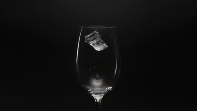 冰冻块掉落空玻璃特写。清爽鸡尾酒准备概念