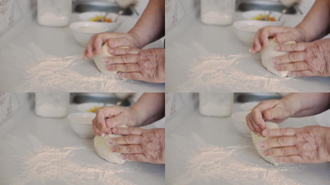 高级妇女用手在白色的厨房桌子上揉面团，背景是模糊的磨碎的苹果和糖。选择性聚焦。用苹果馅制作馅饼的过程