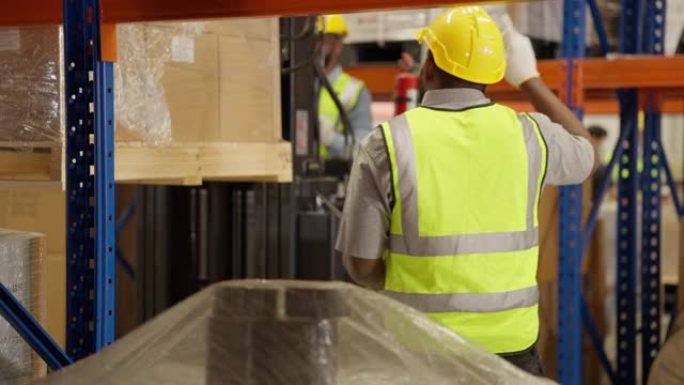 男性仓库工人在仓库检查和控制箱子，专业仓库工人通过叉车堆垛机搬运纸箱，物流和商业出口概念