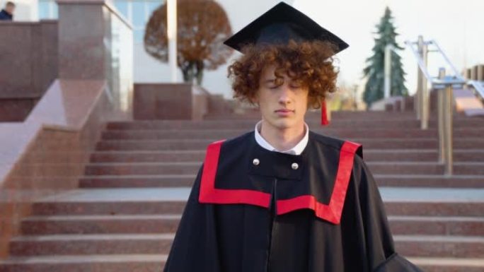 一个年轻的滑稽毕业生在主人的斗篷中纠正了他头上的帽子