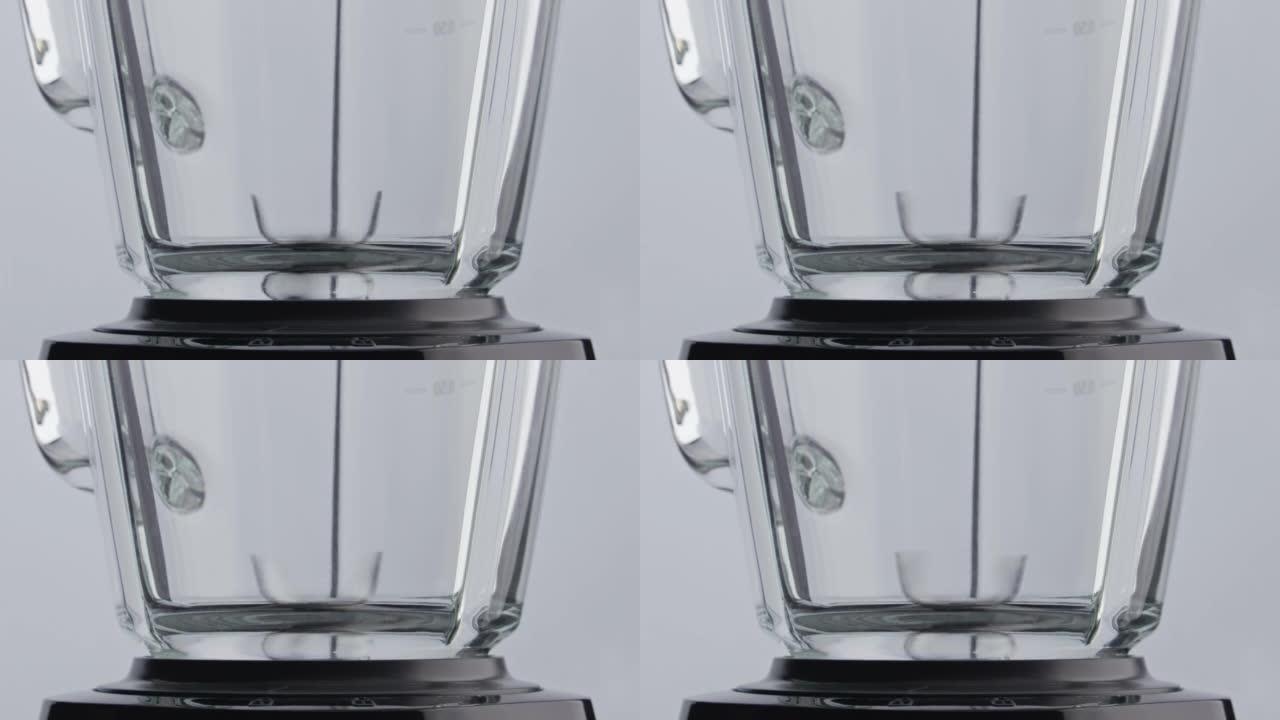 特写搅拌器刀片以超慢动作在空玻璃碗内旋转。