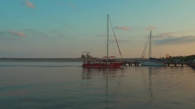 刻赤，克里米亚，刻赤的2021年8月21日堤防，刻赤海峡。夏日傍晚，一艘红色帆船与人一起停泊在码头。