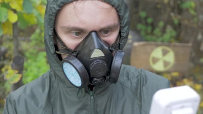 穿着防护服和口罩呼吸器的人使用辐射盖革计数器